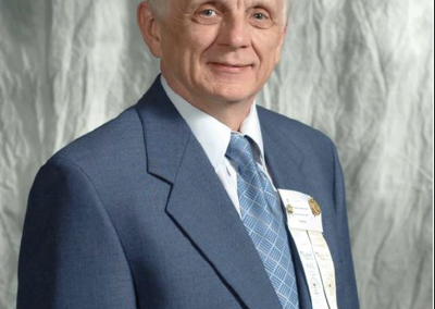Ron Underwood, recipient of the National Speech & Debate Association Ten Diamond Coach Award, wearing a blue suit and ribbons in an official portrait.